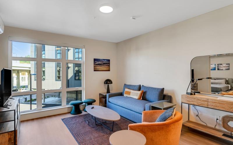 a living room with a blue couch, tables and a chair